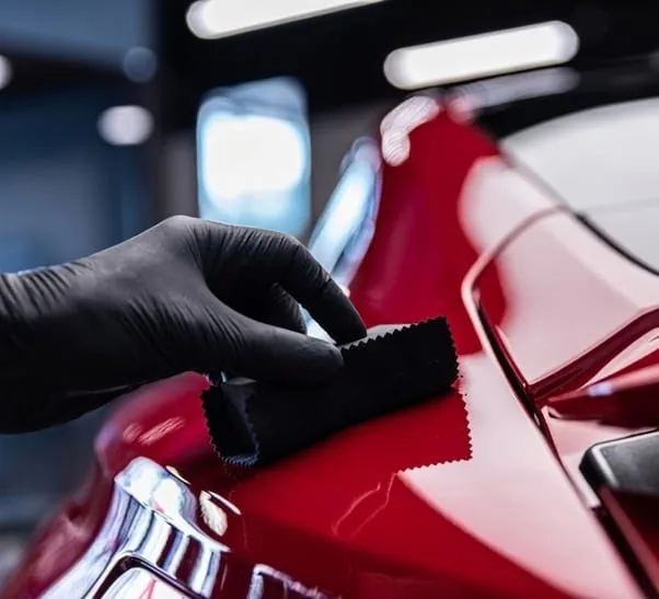 Gloved hand applying ceramic coating to glossy red paint