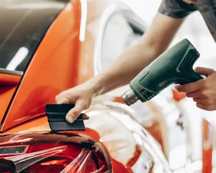 Technician applying paint protection film with a heat gun
